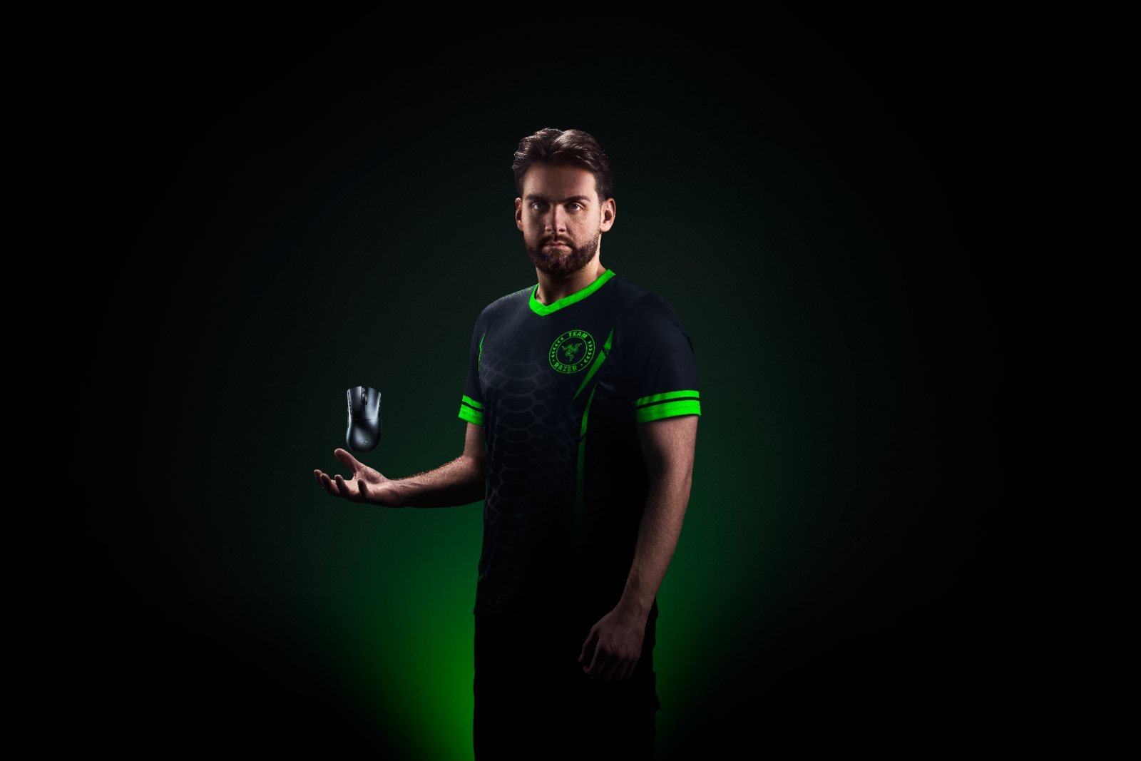 Un giocatore professionista in maglia Team Razer tiene il Razer DeathAdder V4 Pro nero sul palmo aperto, a mostrarne i 56 grammi